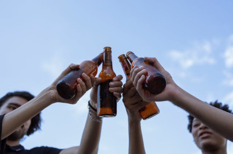 People clinking bottled beer in their hands